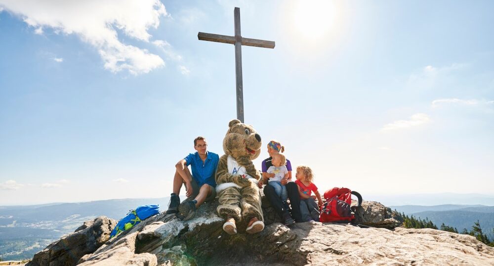 Familie sitzend am Gipfelkreuz